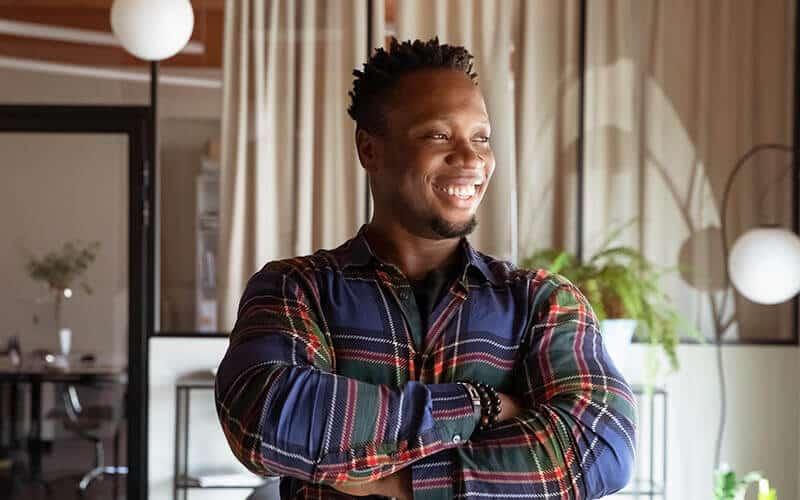 Man in blue green and red checked shirt smiling with crossed arms